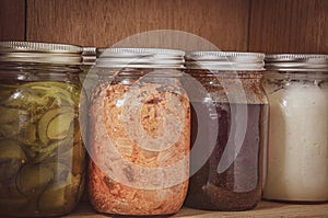 Assortment of fremented,pickled foods and sauces  in glass jars on a wooden shelf