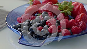Assortment of Fresh Berries on a Blue Glass Plate for Healthy Snacking