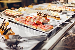 Assortment of fresh desserts displayed in hotel buffet. Variety of cakes in canteen ready for dinner