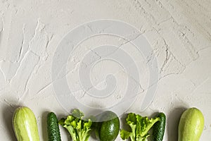 Assortment of fresh green organic vegetables on a concrete background