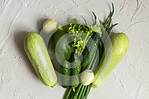 Assortment of fresh green organic vegetables on a concrete background