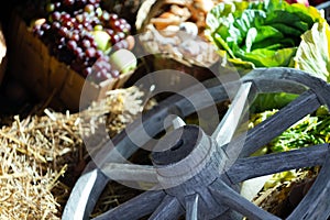 Assortment of fresh vegetables on hay with old wood wheel. Autumn harve