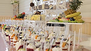 An assortment of fruits, drinks, sweet cakes and cupcakes offered to guests at the wedding reception.