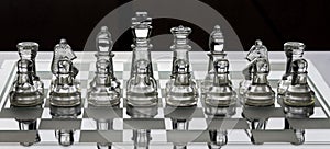 Assortment of glass chess pieces on a board with black and white shade