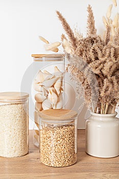 Assortment of grains, cereals and pasta in glass jars on wooden table. Zero waste kitchen storage