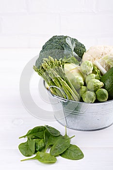 Assortment green vegetables on white table.  Broccoli, cauliflower, brussels sprouts, kohlrabi, avocado, asparagus, spinach.