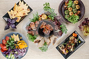 Assortment of grilled meat, Georgian cuisine snacks, cheese, vegetable cuts on a white wooden table. Top view.