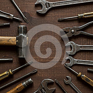 An assortment of hand tools arranged on a dark wooden surface. Visible tools include
