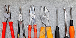 Assortment of hand tools including various pliers on gray background