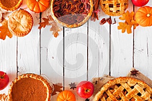 Assortment of homemade autumn pies. Double border on a white wood background.