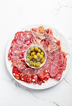 Assortment of Italian and Spanish sliced meat appetizer, prosciutto, salami and ham, with olives