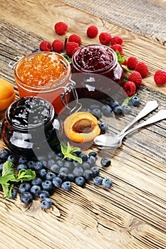 Assortment of jams, seasonal berries, apricot, mint and fruits.