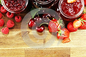 Assortment of jams, seasonal berries, cherry, mint and fruits in glass jar