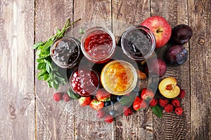 Assortment of jams, seasonal berries, plums, mint and fruits.