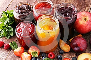 Assortment of jams, seasonal berries, plums, mint and fruits.