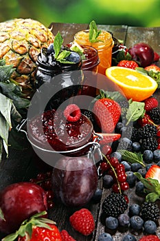 Assortment of jams, seasonal berries, plums, mint and fruits in glass jar