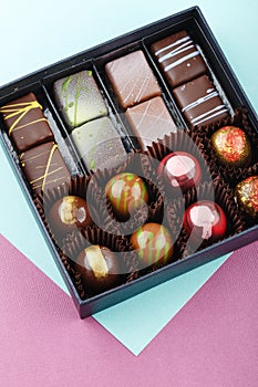 Assortment of luxury bonbons in box on colorful purple and blue