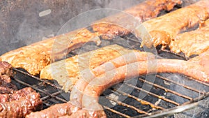 Assortment of marinated meat grilling over the hot coals on a BBQ with sausage, steak.