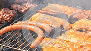 Assortment of marinated meat grilling over the hot coals on a BBQ with sausage, steak.