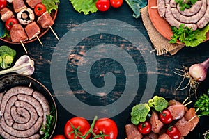 Assortment of meat for barbecue. Sausages, skewers and vegetables. On a wooden background.