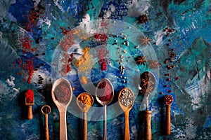 Assortment of natural spices on a vintage spoons over blue concrete background.Top view with copy space