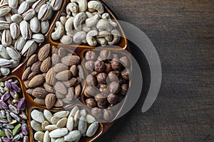 Assortment of nuts in ceramic bowl on a wooden background, close up, top view, copy space. Cashew, hazelnuts, pistachios and