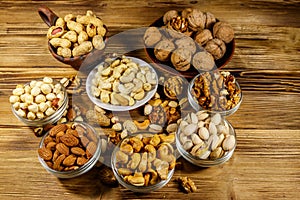 Assortment of nuts on wooden table. Almond, hazelnut, pistachio, peanut, walnut and cashew in small bowls