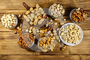 Assortment of nuts on wooden table. Almond, hazelnut, pistachio, peanut, walnut and cashew in small bowls. Top view