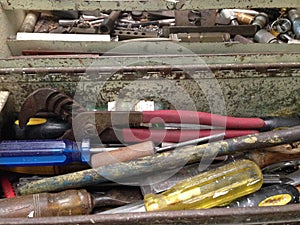 Assortment of old, used screwdrivers and other tools in a metal