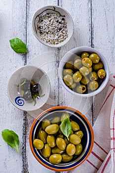 Assortment of olives with herb and sea salt on white wooden bac
