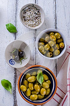 Assortment of olives with herb and sea salt on white wooden back