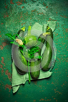 Assortment of organic courgettes and zucchinis on green background
