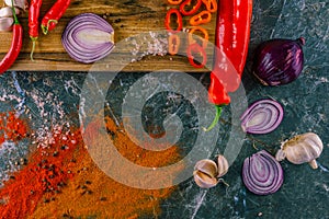 Assortment of peppers, garlic and onions on a stone countertop