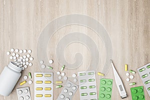 Assortment of pharmaceutical medicine pills, tablets, capsules and thermometer over empty wooden background. Medication concept.