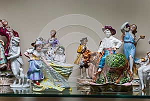 Assortment of rare porcelain figurines on glass shelf