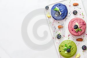 Assortment of raw vegan cheesecakes with matcha, acai, butterfly pea tea, berries, mint and nuts. healthy vegan food