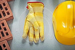 Assortment of red bricks hard hat protective gloves on concrete