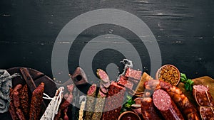 Assortment of salami and snacks. Sausage Fouet, sausages, salami, paperoni. On a black wooden background.
