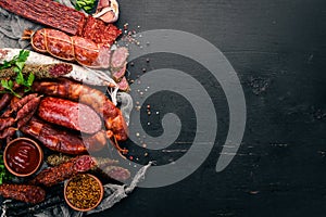 Assortment of salami and snacks. Sausage Fouet, sausages, salami, paperoni. On a black wooden background.