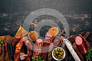 Assortment of salami and snacks. Sausage Fouet, sausages, salami, paperoni. On a black wooden background.