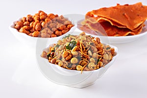 Assortment salty crunchy indian mix Nimco or Namkeen, spicy coated peanut and pappadam white bowl wooden background