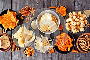 Assortment of salty snacks, top view table scene over wood