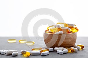 Assortment scattered pharmaceutical medicine tablets, pills, drugs in wooden bowl on gray background. White food dietary