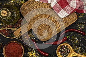 An assortment of spices on a black background, a cutting board