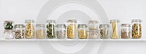 Assortment of uncooked groceries in glass jars arranged on shelf photo