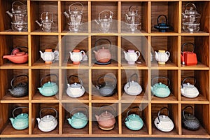 assortment of various ceramic and glass teapots on the cabinet as an interior decoration at home or in a cafe