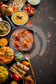 Assortment of various kinds of Indian cousine on dark rusty table