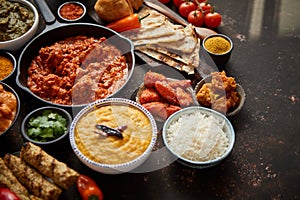 Assortment of various kinds of Indian cousine on dark rusty table