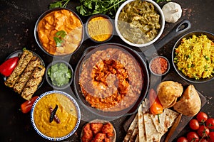 Assortment of various kinds of Indian cousine on dark rusty table