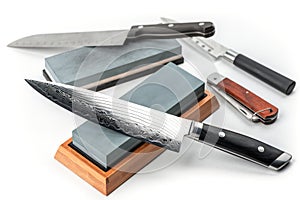 Assortment of various knives and whetstones on white background